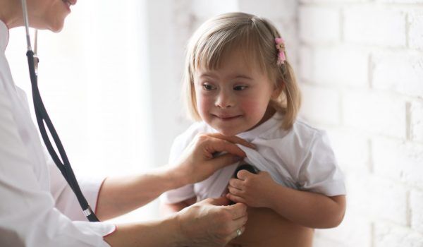 Cardiologist listens to the heart of a child with Down syndrome, the concept of health and medical examination of children with special needs