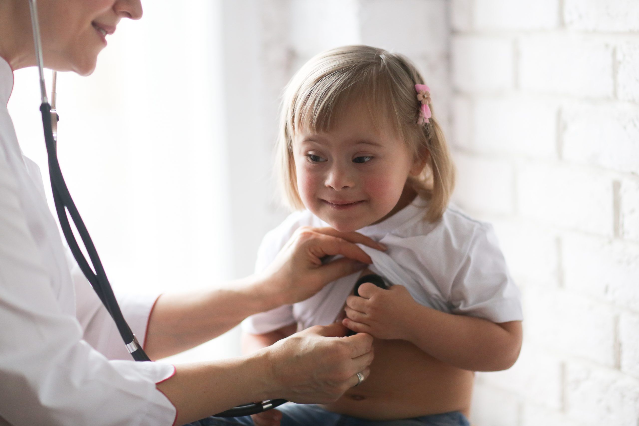 Cardiologist listens to the heart of a child with Down syndrome, the concept of health and medical examination of children with special needs